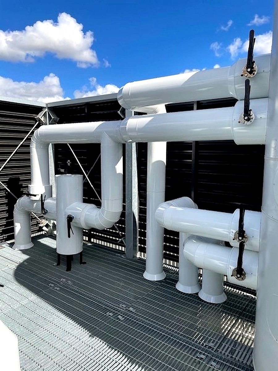 White sheet metal cladding on roof-mounted insulated pipework exposed to weather